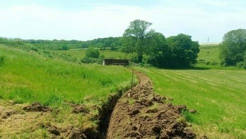 Tranchée pour réseau à travers une prairie